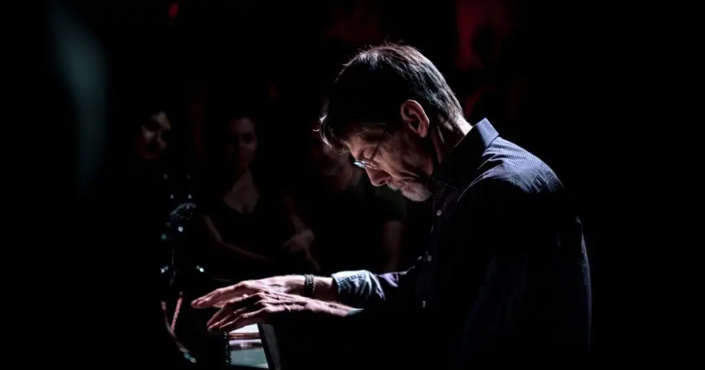 Fred Hersch at the piano playing in moody and dark light
