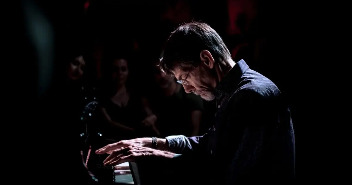 Fred Hersch at the piano playing in moody and dark light